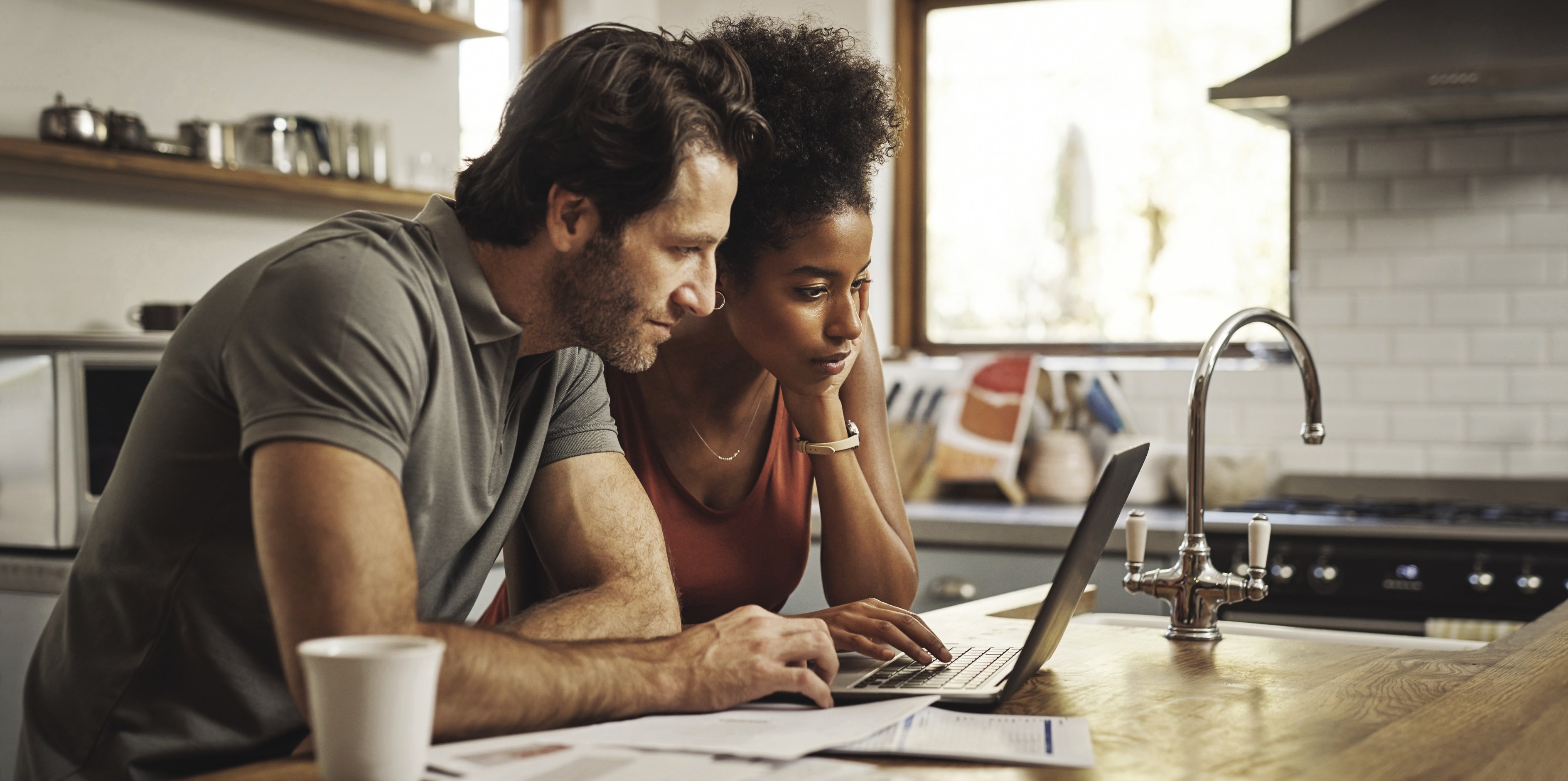 Cropped shot of a couple using their laptop and going through paperwork at home